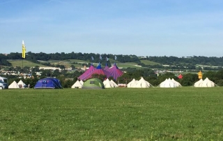 A field with tents in the distance at a festival.